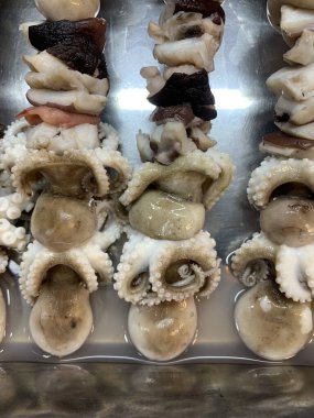 Açık hava yiyecek pazarında servis edilen bambu çubuğuyla ızgara yapılmış lezzetli kalamar ve ahtapot. egzotik Asya yemekleri. 