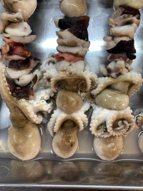 Açık hava yiyecek pazarında servis edilen bambu çubuğuyla ızgara yapılmış lezzetli kalamar ve ahtapot. egzotik Asya yemekleri. 