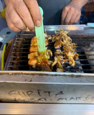 Açık hava yiyecek pazarında servis edilen bambu çubuğuyla ızgara yapılmış lezzetli kalamar ve ahtapot. egzotik Asya yemekleri. 