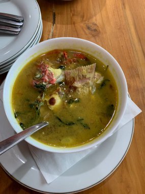 Kırmızı Snapper balığı baharatlı çorba sarımsak, domates, sebze ve acı biber sosu ve ahşap masadaki çeşitli baharatlarla dolu beyaz bir kasede ekşi köri. Lezzetli yemek.