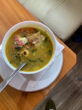 Kırmızı Snapper balığı baharatlı çorba sarımsak, domates, sebze ve acı biber sosu ve ahşap masadaki çeşitli baharatlarla dolu beyaz bir kasede ekşi köri. Lezzetli yemek.