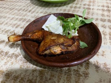 Ayam bakar Penyet, taze sebze, salatalık ve fesleğen yapraklı sıcak biberli kızarmış tavuktur.