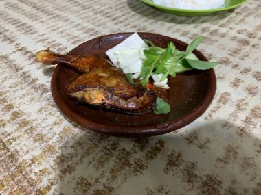 Ayam bakar Penyet, taze sebze, salatalık ve fesleğen yapraklı sıcak biberli kızarmış tavuktur.