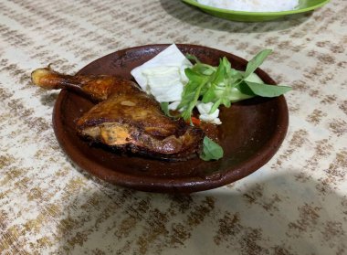 Ayam bakar Penyet, taze sebze, salatalık ve fesleğen yapraklı sıcak biberli kızarmış tavuktur.