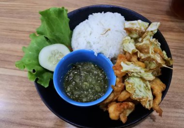 Ayam bakar Penyet, taze sebze, salatalık ve fesleğen yapraklı sıcak biberli kızarmış tavuktur.