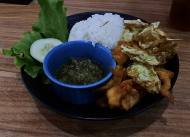 Ayam bakar Penyet, taze sebze, salatalık ve fesleğen yapraklı sıcak biberli kızarmış tavuktur.