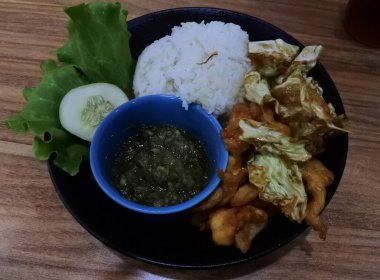 Ayam bakar Penyet, taze sebze, salatalık ve fesleğen yapraklı sıcak biberli kızarmış tavuktur.