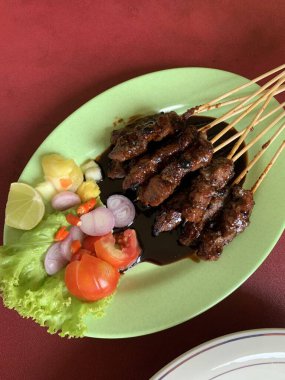 Keçi ve geyik eti satay baharatlı, sonra ızgarada mükemmelce pişirildi ve dilimlenmiş lahana, domates, arpacık soğanı, arnavut biberi ve limonla servis edildi..