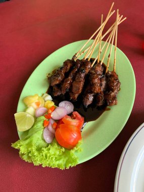 Keçi ve geyik eti satay baharatlı, sonra ızgarada mükemmelce pişirildi ve dilimlenmiş lahana, domates, arpacık soğanı, arnavut biberi ve limonla servis edildi..