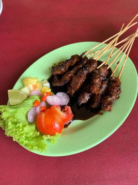 Keçi ve geyik eti satay baharatlı, sonra ızgarada mükemmelce pişirildi ve dilimlenmiş lahana, domates, arpacık soğanı, arnavut biberi ve limonla servis edildi..