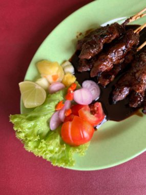 Keçi ve geyik eti satay baharatlı, sonra ızgarada mükemmelce pişirildi ve dilimlenmiş lahana, domates, arpacık soğanı, arnavut biberi ve limonla servis edildi..