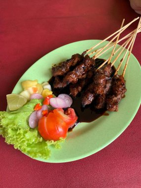Keçi ve geyik eti satay baharatlı, sonra ızgarada mükemmelce pişirildi ve dilimlenmiş lahana, domates, arpacık soğanı, arnavut biberi ve limonla servis edildi..