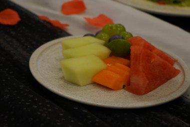 Kahvaltıda beyaz tabakta tropikal konseptle karışık taze meyve yakın çekim. Bir sürü karpuz, kavun, üzüm, ananas. ve papaya. seçici odak.