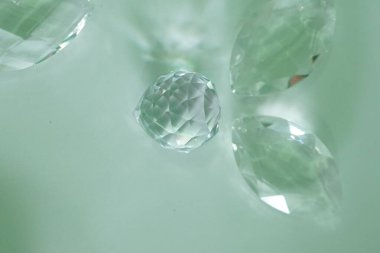 Temiz kristal cam top avizesi, yeşil arka planda çok yüzlü bir güneş tutucu.