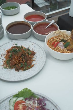 Pişmiş erişteyle kızartılmış beyaz tabak yeşil sebzeler taze marul, salatalık, brokoli ve domates dilimi ile karıştırılmış tavuk, yumurta veya tofu ile süslenmiş. Çatal eriştenin üstüne konur..