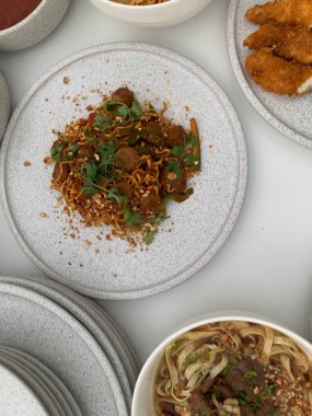 Pişmiş erişteyle kızartılmış beyaz tabak yeşil sebzeler taze marul, salatalık, brokoli ve domates dilimi ile karıştırılmış tavuk, yumurta veya tofu ile süslenmiş. Çatal eriştenin üstüne konur..