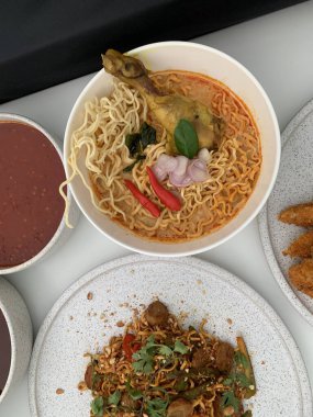 Pişmiş erişteyle kızartılmış beyaz tabak yeşil sebzeler taze marul, salatalık, brokoli ve domates dilimi ile karıştırılmış tavuk, yumurta veya tofu ile süslenmiş. Çatal eriştenin üstüne konur..