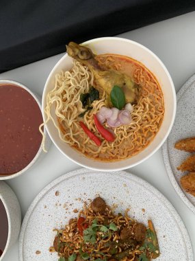 Pişmiş erişteyle kızartılmış beyaz tabak yeşil sebzeler taze marul, salatalık, brokoli ve domates dilimi ile karıştırılmış tavuk, yumurta veya tofu ile süslenmiş. Çatal eriştenin üstüne konur..