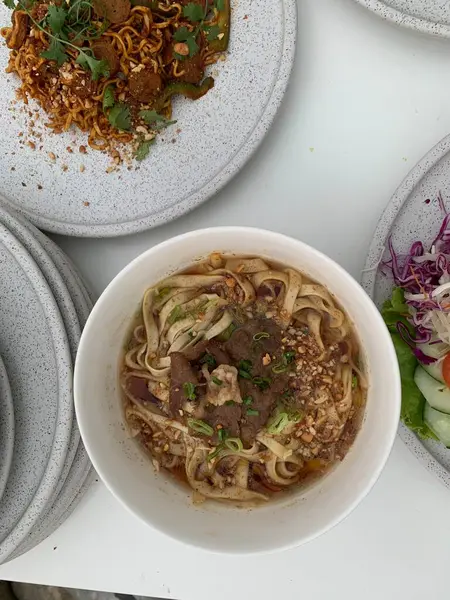 Pişmiş erişteyle kızartılmış beyaz tabak yeşil sebzeler taze marul, salatalık, brokoli ve domates dilimi ile karıştırılmış tavuk, yumurta veya tofu ile süslenmiş. Çatal eriştenin üstüne konur..