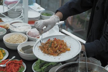 Pişmiş erişteyle kızartılmış beyaz tabak yeşil sebzeler taze marul, salatalık, brokoli ve domates dilimi ile karıştırılmış tavuk, yumurta veya tofu ile süslenmiş. Çatal eriştenin üstüne konur..