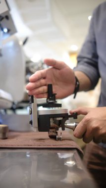 Kafede kahve telvesi hazırlamak için modern öğütücü makine kullanan kişi dijital ekran ve cilalanmış metal kaplama özellikleri kullanıyor.  