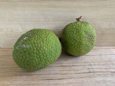 Moraceae ailesinin tüm ekmek meyvesi üyeleri Artocarpus altilis ve dilimler ahşap yüzeyde sergilenir. Nişastalı, patates gibi kızarmasıyla tanınır. yiyecek fotoğrafçılığı, meyve fotoğrafçılığı yiyecek ve içecek.