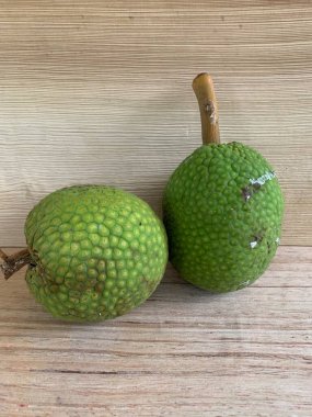 Moraceae ailesinin tüm ekmek meyvesi üyeleri Artocarpus altilis ve dilimler ahşap yüzeyde sergilenir. Nişastalı, patates gibi kızarmasıyla tanınır. yiyecek fotoğrafçılığı, meyve fotoğrafçılığı yiyecek ve içecek.