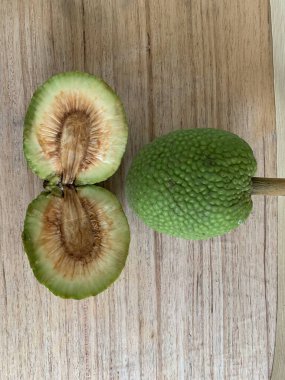 Moraceae ailesinin tüm ekmek meyvesi üyeleri Artocarpus altilis ve dilimler ahşap yüzeyde sergilenir. Nişastalı, patates gibi kızarmasıyla tanınır. yiyecek fotoğrafçılığı, meyve fotoğrafçılığı yiyecek ve içecek.