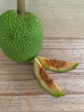Moraceae ailesinin tüm ekmek meyvesi üyeleri Artocarpus altilis ve dilimler ahşap yüzeyde sergilenir. Nişastalı, patates gibi kızarmasıyla tanınır. yiyecek fotoğrafçılığı, meyve fotoğrafçılığı yiyecek ve içecek.