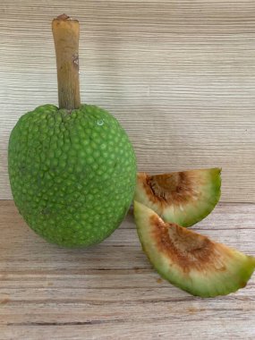 Moraceae ailesinin tüm ekmek meyvesi üyeleri Artocarpus altilis ve dilimler ahşap yüzeyde sergilenir. Nişastalı, patates gibi kızarmasıyla tanınır. yiyecek fotoğrafçılığı, meyve fotoğrafçılığı yiyecek ve içecek.