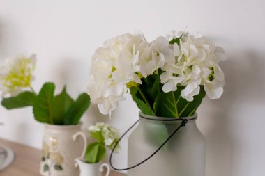 Çiçek desenli ahşap mutfak. Sıcak ev dekorasyonu. Mutfak gereçleri, bulaşıklar ve masada bir tabak. Mutfak masası yemek odasında. Vazoda çiçekler olan şık bir mutfak..