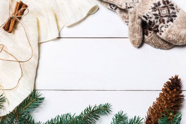 Noel kompozisyonu. Örülmüş battaniye, çam kozalakları, tahta beyaz arka planda köknar dalları. Düz yatış, üst görünüm