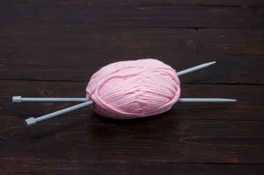 Hasır sepette örgü iğneleriyle bobinlerdeki yün iplikleri açık arkaplanda.