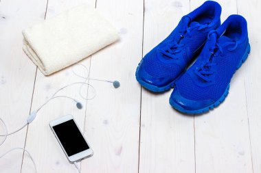 Spor ayakkabılar, kulaklıklar ve ahşap arka planda telefon..