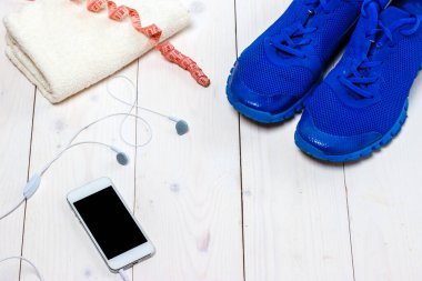 Spor ayakkabılar, kulaklıklar ve ahşap arka planda telefon..