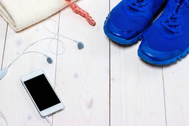 Spor ayakkabılar, kulaklıklar ve ahşap arka planda telefon..