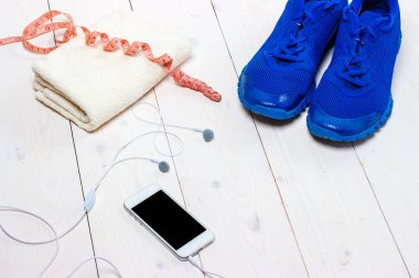 Spor ayakkabılar, kulaklıklar ve ahşap arka planda telefon..