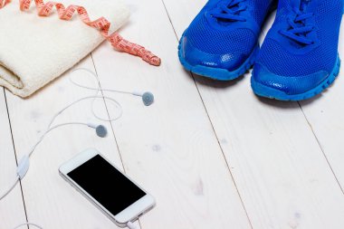 Spor ayakkabılar, kulaklıklar ve ahşap arka planda telefon..