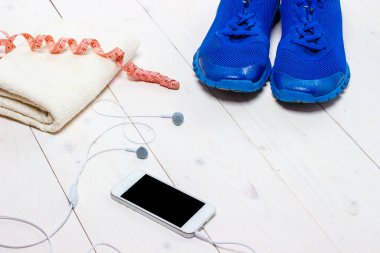 Spor ayakkabılar, kulaklıklar ve ahşap arka planda telefon..