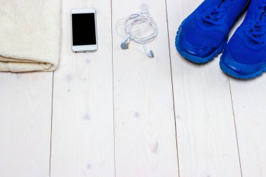 Spor ayakkabılar, kulaklıklar ve ahşap arka planda telefon..