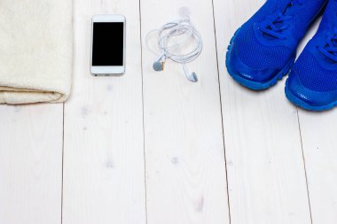 Spor ayakkabılar, kulaklıklar ve ahşap arka planda telefon..