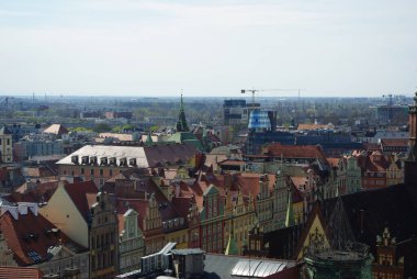Şehir siluetinin, büyük bir kilise kulesinin ve renkli çatıların bulunduğu bir şehir manzarası..