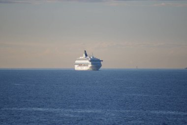 Açık bir gökyüzünün altında seyreden büyük bir yolcu gemisi görülüyor..