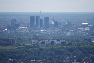Gökdelenlerin ve mavi gökyüzünün altındaki kentsel binaların yer aldığı şehir manzarasının panoramik bir görüntüsü..