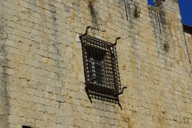 A rusted metal grate over a small, rectangular window on an old stone building. clipart