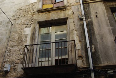 Paslı balkonlu, penceresi ve parmaklığı olan eski bir bina..