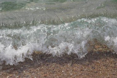 Büyük bir dalga kumlu bir plaja çarpıyor..