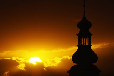 Gün batımı ve arkasında dolunay olan çarpıcı bir kilise silueti..