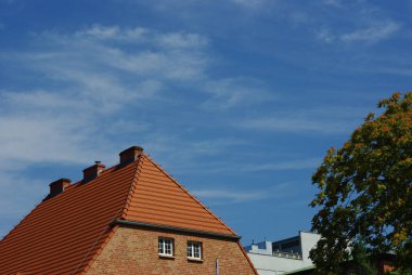 Mavi gökyüzünün altına kurulmuş dik, sivri çatılı bir evin resimsel bir görüntüsü..