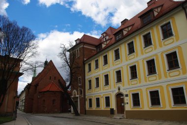 Tarihsel Avrupa mimarisinin yer aldığı bir sokak sahnesinde birden fazla penceresi ve eski bir kilisesi olan büyük bir bina yer alıyor.. 